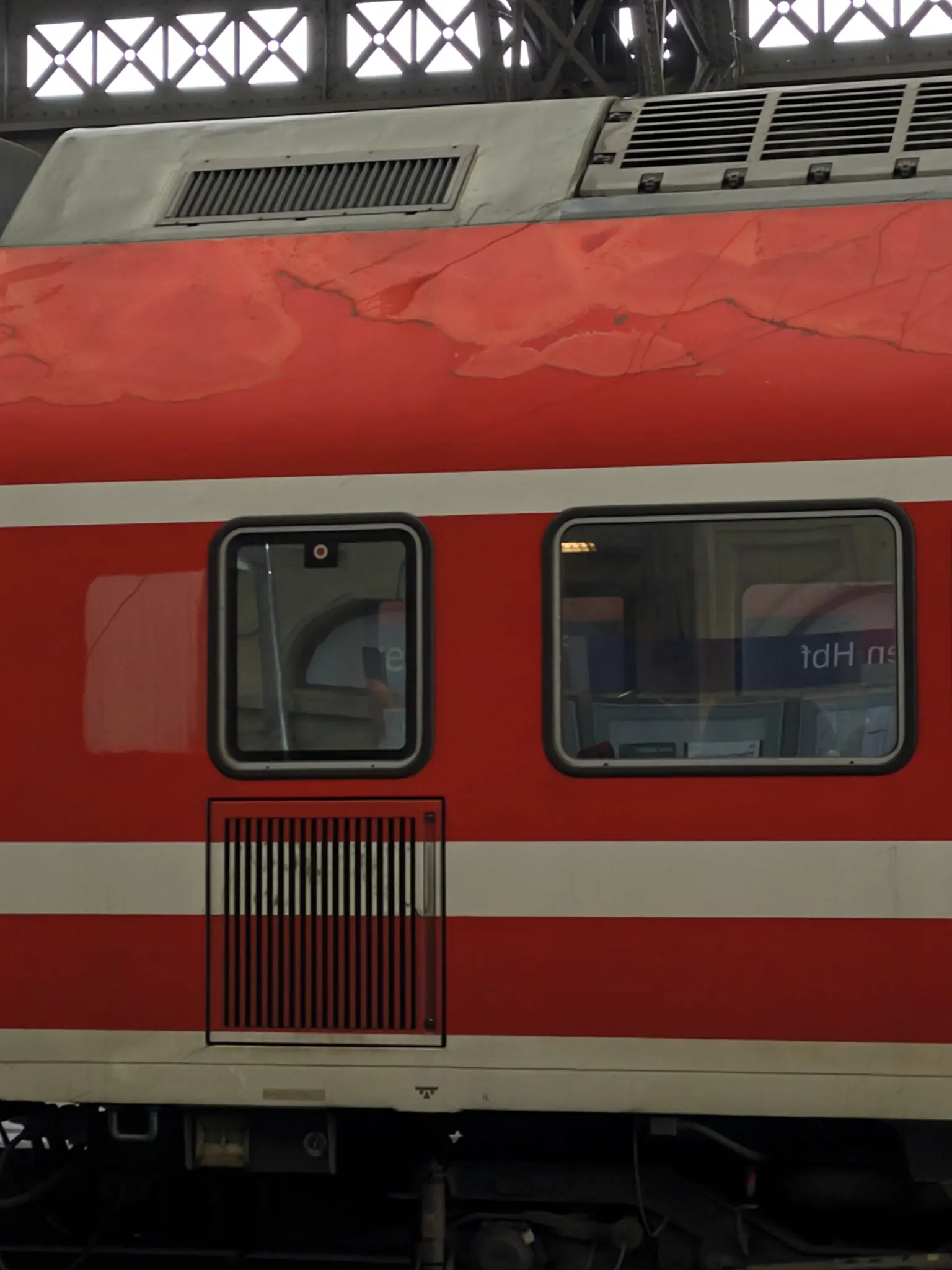 A red and white DB Regio wagon. The paint is deeply faded and cracked at the top of the train.