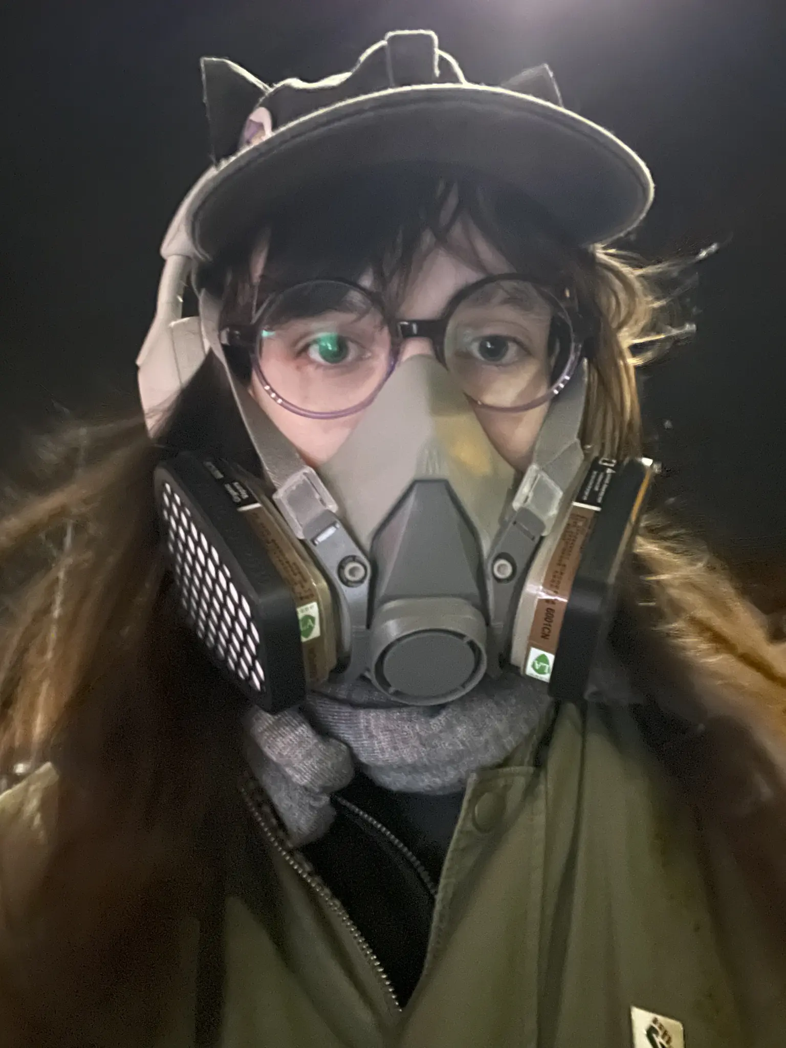 Low-angle close up selfie of flori wearing its half face respirator with two side mounted filters